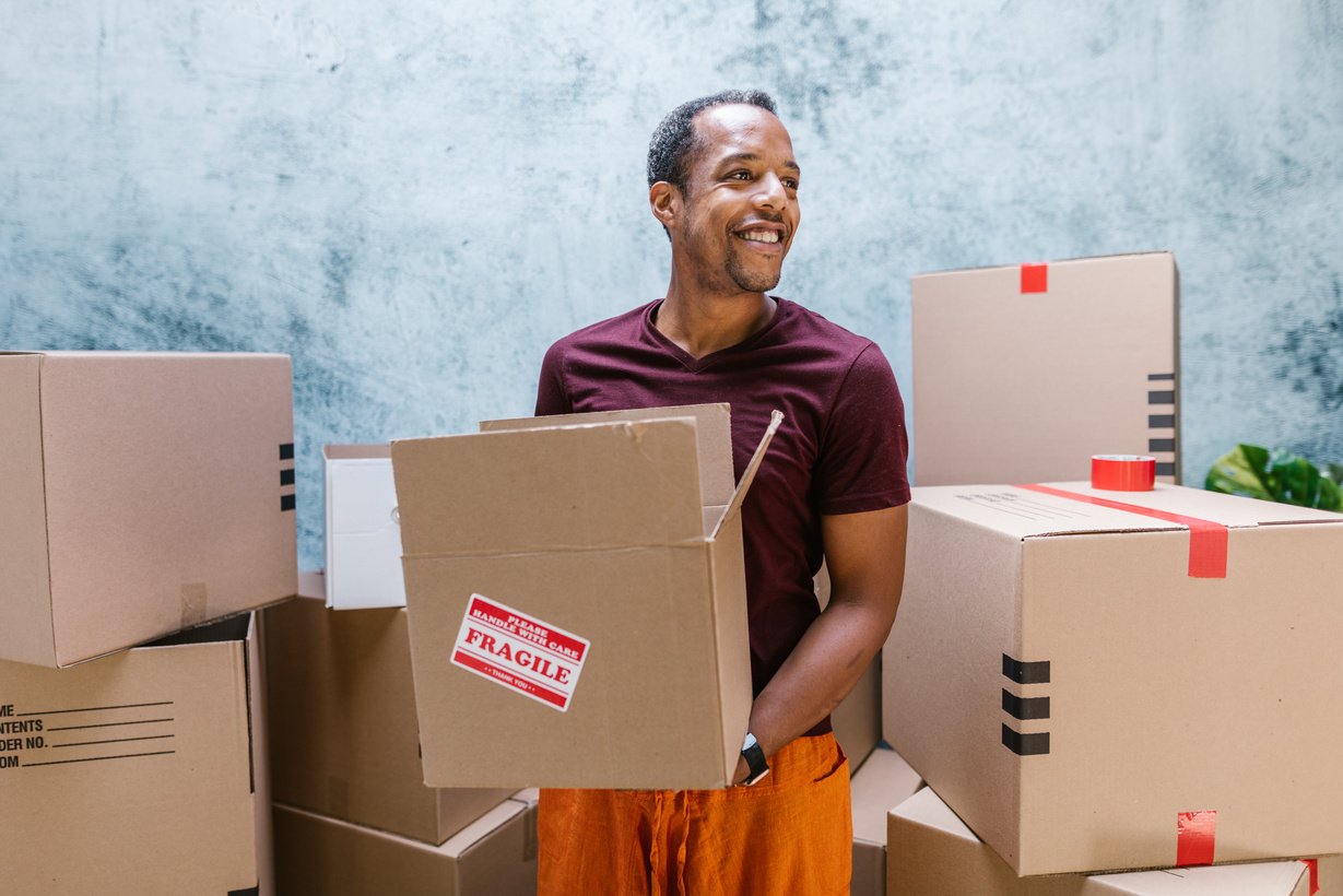 Man in Red Crew Neck T-shirt Holding Brown Cardboard Box